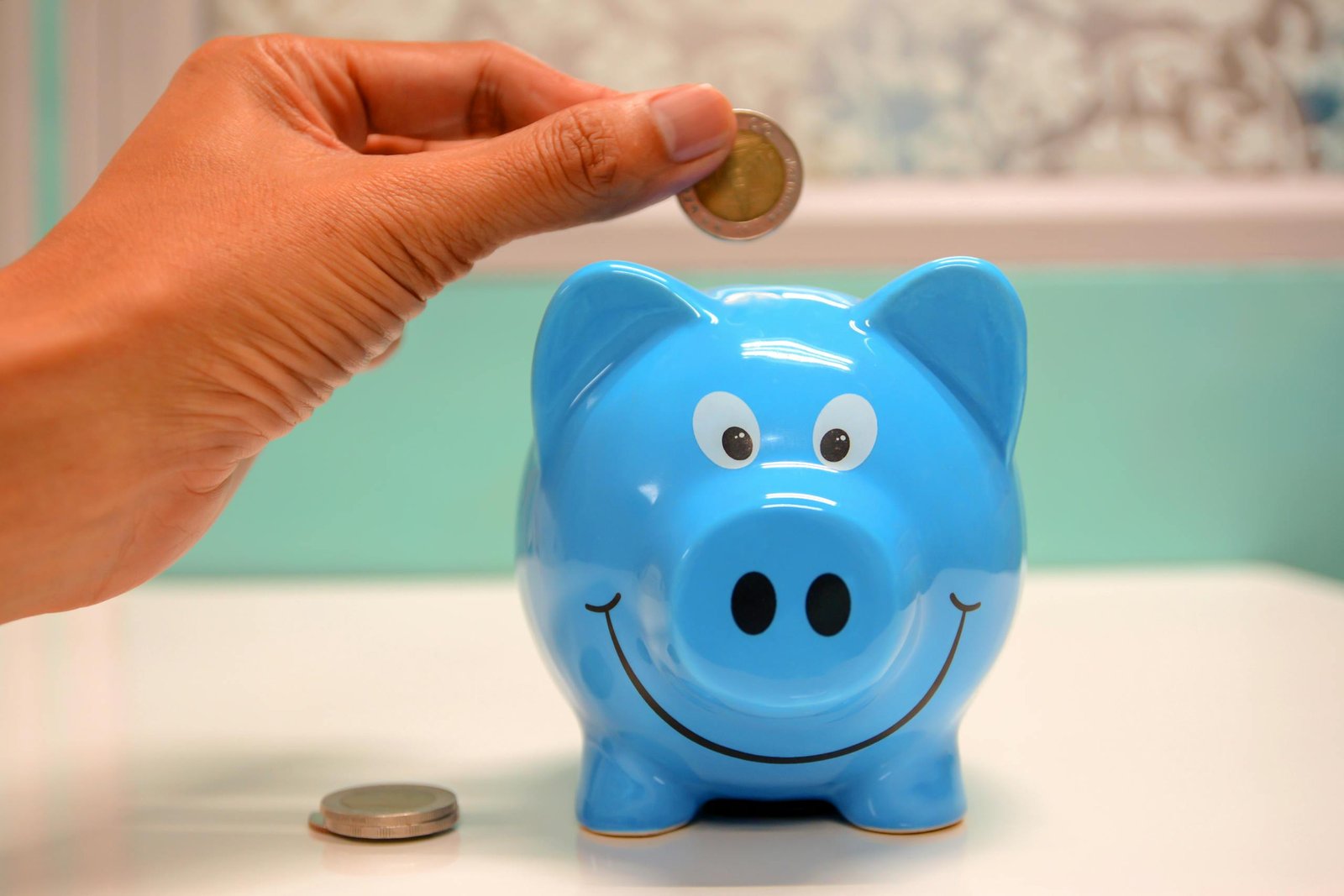 SBI Magnum SIF, Hand inserting a coin into a blue piggy bank for savings and money management.
