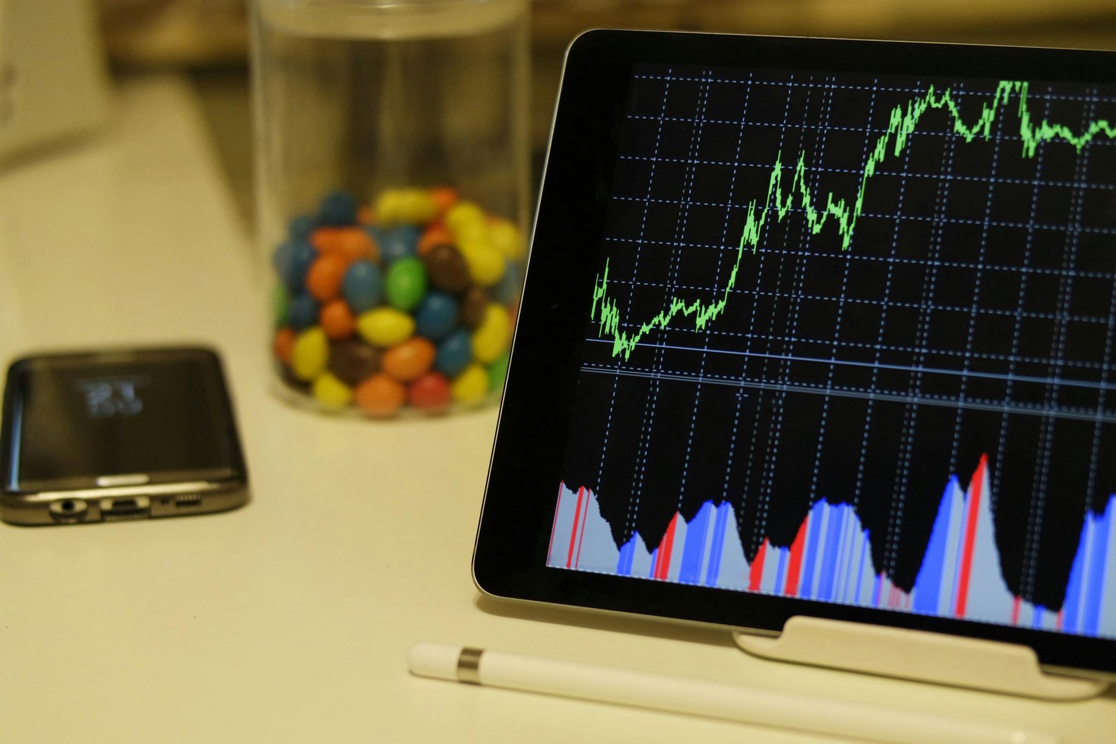 Indian Stock Market, Tablet display of stock market data with smartphone and colorful candies on desk.